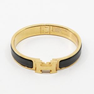 Armband Hermés Clic H bracelet med svart emalj och guldpläterad metall, Ø6cm, modell: ST0118